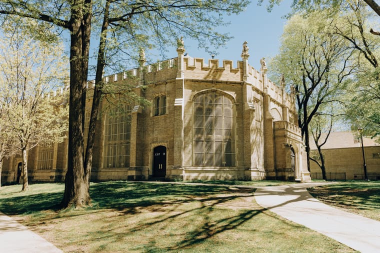 A historic stone library building framed by spring trees