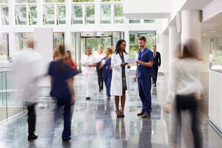 A bright modern hospital lobby with staff and visitors
